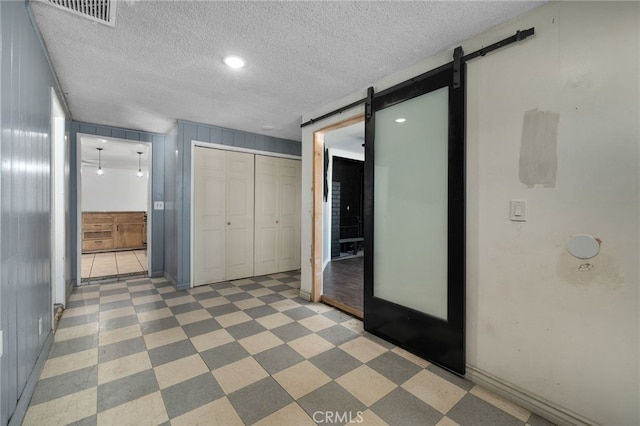 hallway with a barn door and a textured ceiling