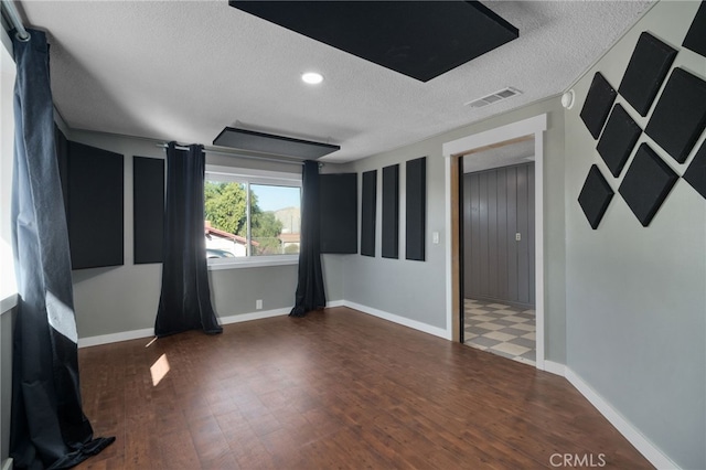 empty room featuring a textured ceiling and dark wood-type flooring