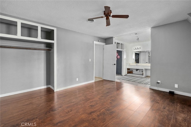 unfurnished bedroom with ensuite bathroom, a textured ceiling, ceiling fan, dark hardwood / wood-style floors, and a closet