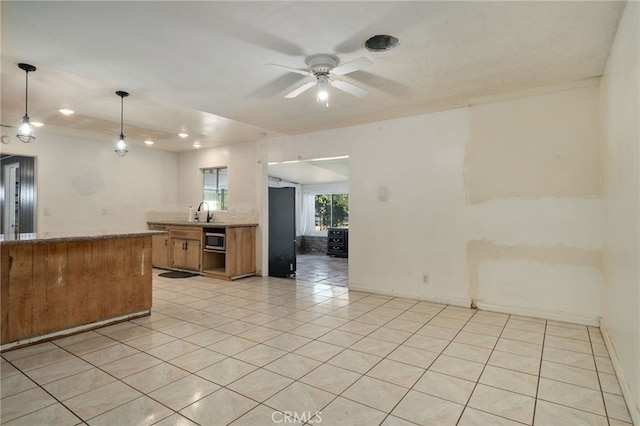 kitchen with pendant lighting, stainless steel microwave, black refrigerator, ceiling fan, and light tile patterned flooring