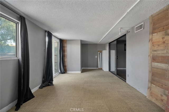 carpeted empty room with a textured ceiling