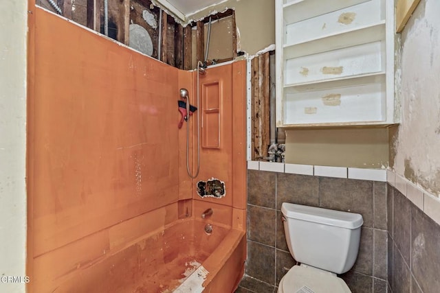 bathroom with toilet, tile walls, and washtub / shower combination