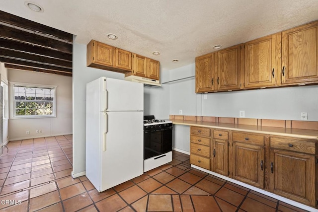 kitchen with dark tile patterned floors, beamed ceiling, and white appliances