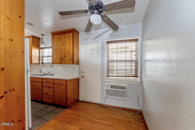 kitchen featuring an AC wall unit, decorative light fixtures, tasteful backsplash, sink, and light wood-type flooring