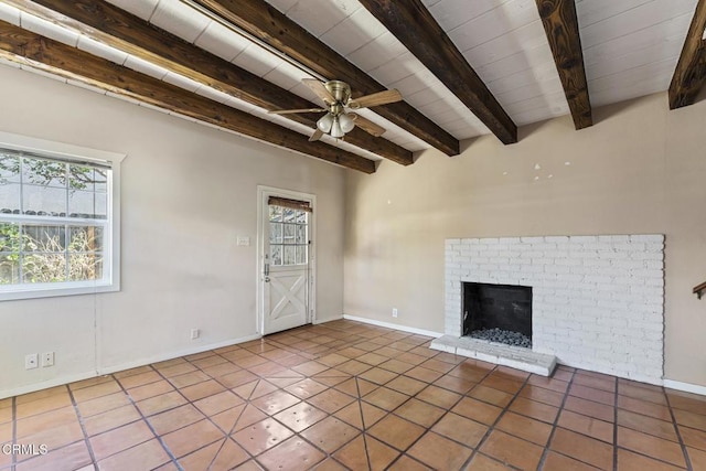 unfurnished living room featuring a brick fireplace, tile patterned flooring, beam ceiling, and ceiling fan