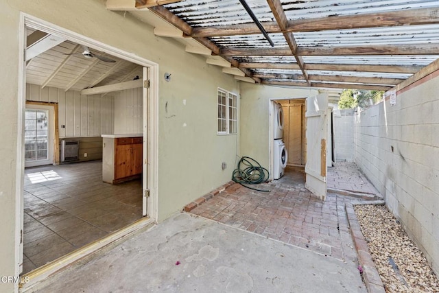 view of patio / terrace with stacked washer / dryer and heating unit