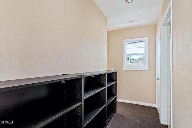 hallway with dark colored carpet