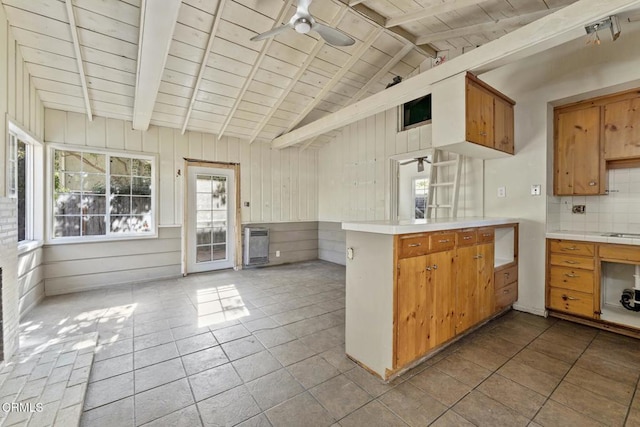 kitchen with light tile patterned floors, wood ceiling, kitchen peninsula, backsplash, and vaulted ceiling with beams