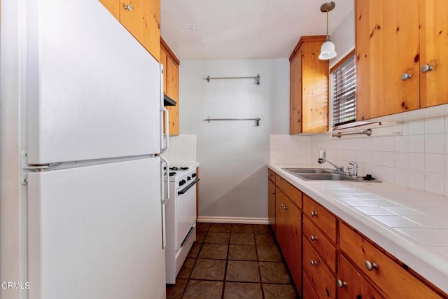 kitchen with white appliances, tile counters, decorative light fixtures, tasteful backsplash, and sink