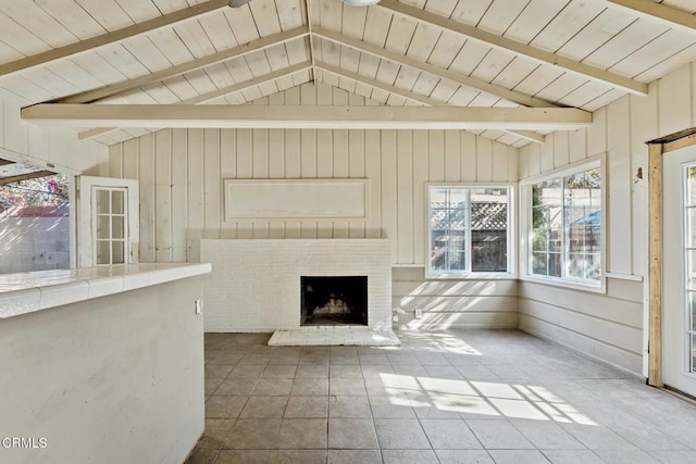 unfurnished living room with vaulted ceiling with beams, a fireplace, tile patterned floors, and wood walls