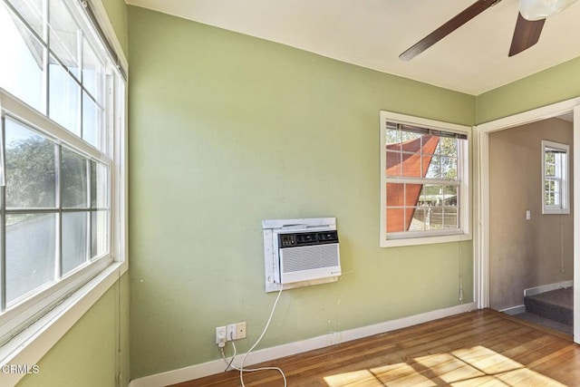 spare room featuring light wood-type flooring, ceiling fan, and a wall unit AC