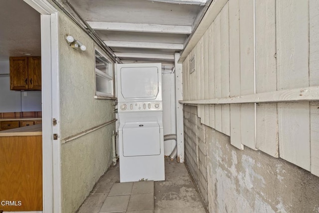 basement featuring stacked washing maching and dryer