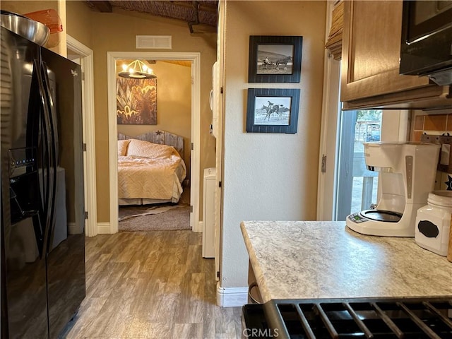 kitchen featuring black fridge, hardwood / wood-style floors, and decorative light fixtures