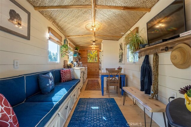 mudroom with light hardwood / wood-style flooring, brick ceiling, and wood walls