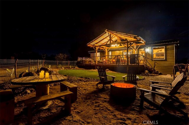 patio at night featuring a wooden deck, a gazebo, and an outdoor fire pit