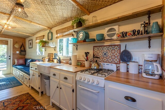 kitchen with white cabinetry, wood counters, white gas range, and light wood-type flooring