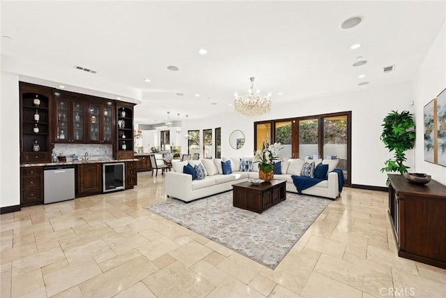 living room with a notable chandelier, indoor bar, wine cooler, and french doors