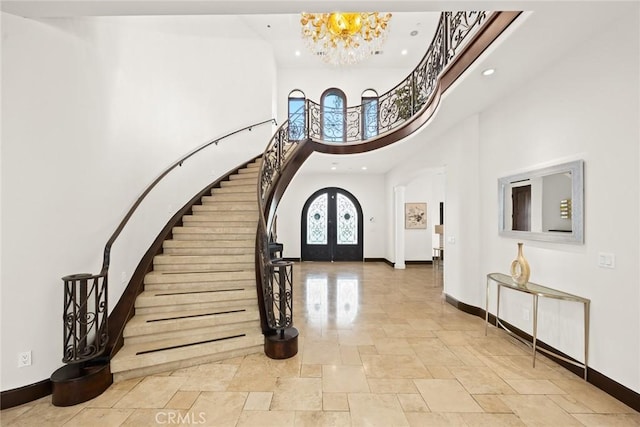 entryway featuring french doors, an inviting chandelier, and a high ceiling