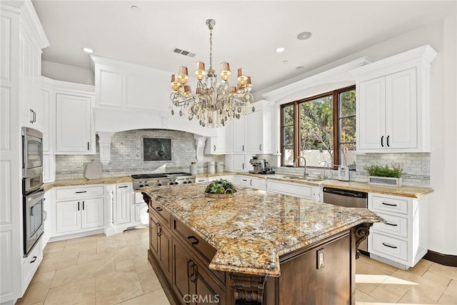 kitchen featuring appliances with stainless steel finishes, backsplash, sink, a kitchen island, and hanging light fixtures