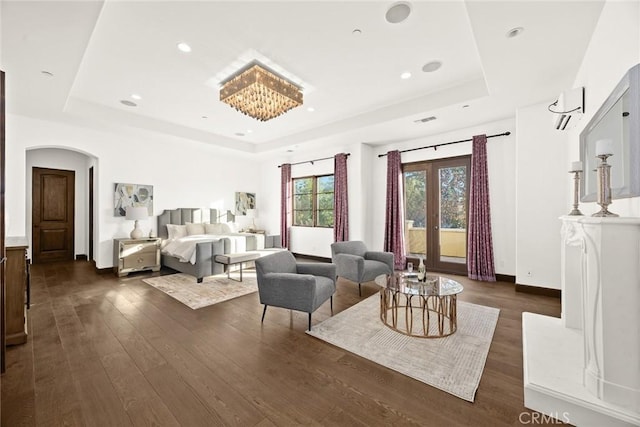 bedroom featuring french doors, a raised ceiling, and dark wood-type flooring