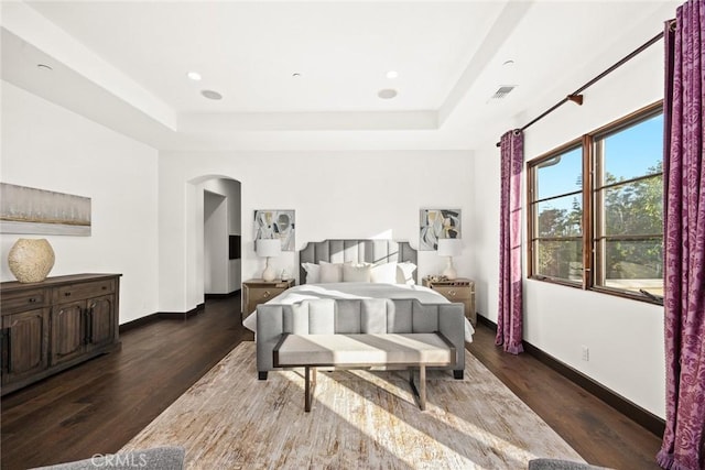 bedroom with a tray ceiling and dark hardwood / wood-style floors