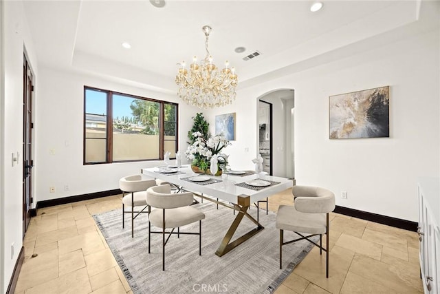 dining space with a tray ceiling and a chandelier