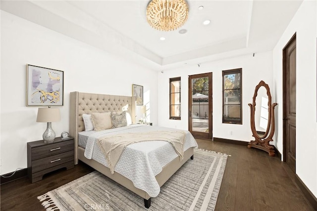 bedroom with dark hardwood / wood-style flooring and a tray ceiling