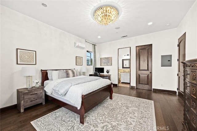 bedroom featuring dark wood-type flooring, electric panel, an inviting chandelier, ensuite bathroom, and a wall mounted AC