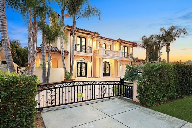 mediterranean / spanish-style house with a balcony and french doors