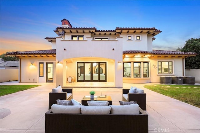 back house at dusk featuring outdoor lounge area, french doors, a patio, and central air condition unit