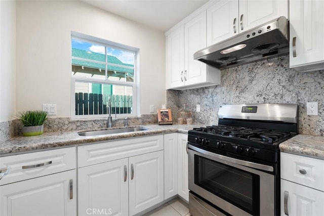 kitchen with gas range, sink, light stone counters, decorative backsplash, and white cabinets