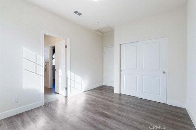 unfurnished bedroom with dark wood-type flooring and a closet