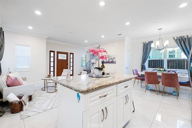 kitchen with ornamental molding, white cabinets, a chandelier, a kitchen island, and hanging light fixtures