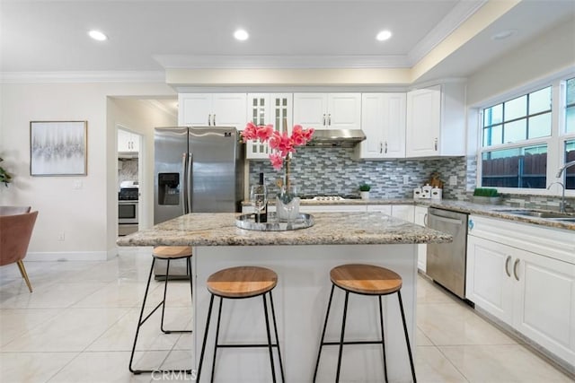 kitchen featuring a kitchen island, light stone counters, sink, and appliances with stainless steel finishes