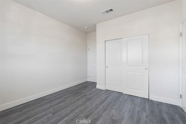 unfurnished bedroom featuring a closet and dark wood-type flooring