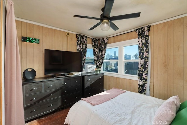 bedroom featuring ceiling fan, wood walls, and dark wood-type flooring