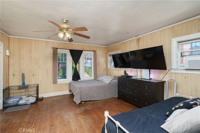 bedroom featuring dark hardwood / wood-style floors, multiple windows, wooden walls, and ceiling fan