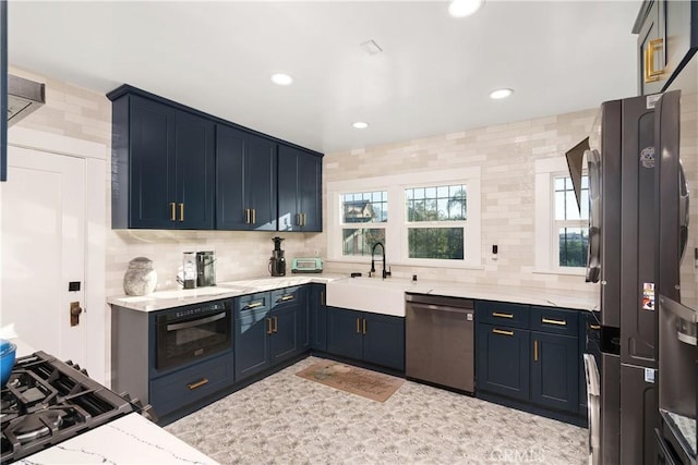 kitchen with backsplash, light stone countertops, sink, and appliances with stainless steel finishes