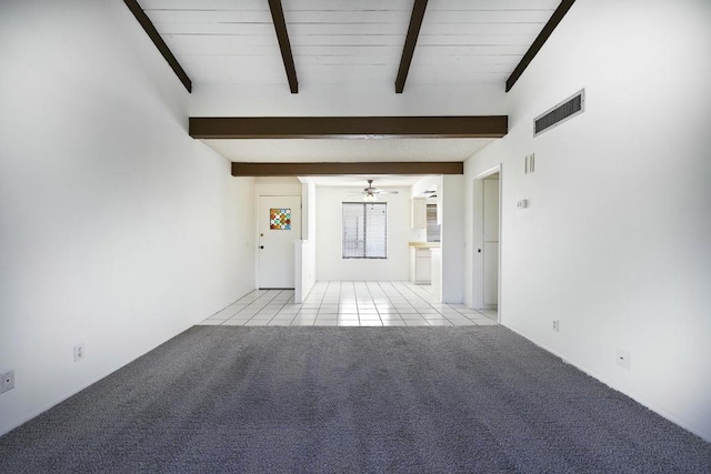 spare room with beam ceiling, ceiling fan, and light carpet