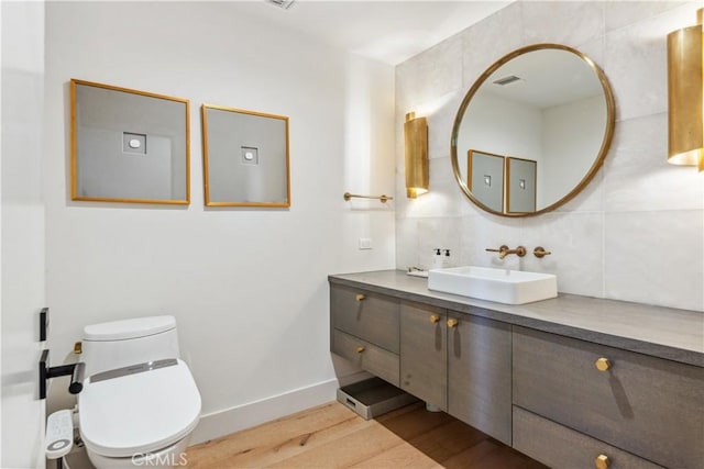 bathroom with hardwood / wood-style floors, vanity, toilet, and tasteful backsplash