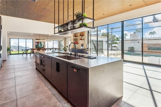 kitchen featuring dark brown cabinetry, a spacious island, sink, light tile patterned floors, and pendant lighting