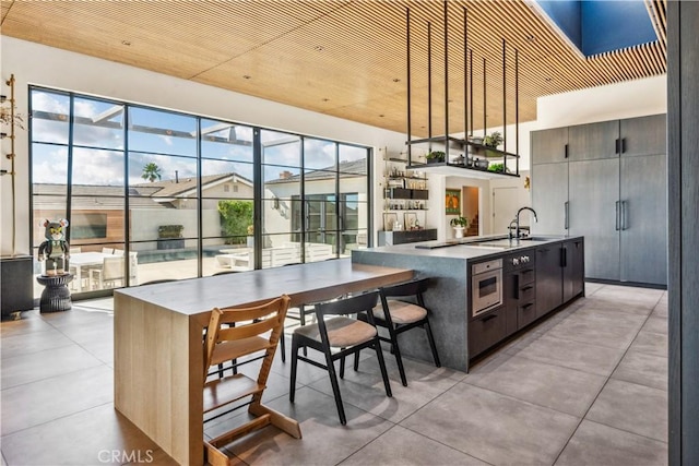 kitchen featuring a kitchen breakfast bar, sink, an island with sink, decorative light fixtures, and dark brown cabinets