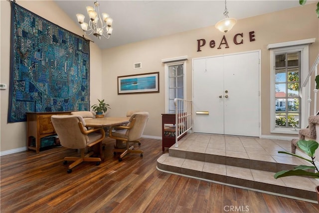 dining area featuring wood-type flooring, a notable chandelier, and vaulted ceiling