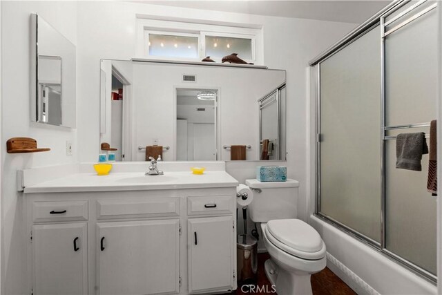 full bathroom featuring bath / shower combo with glass door, toilet, and vanity