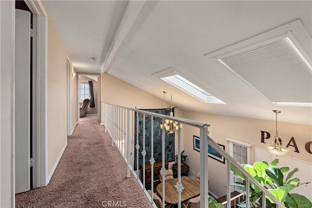 corridor with carpet, a notable chandelier, and vaulted ceiling