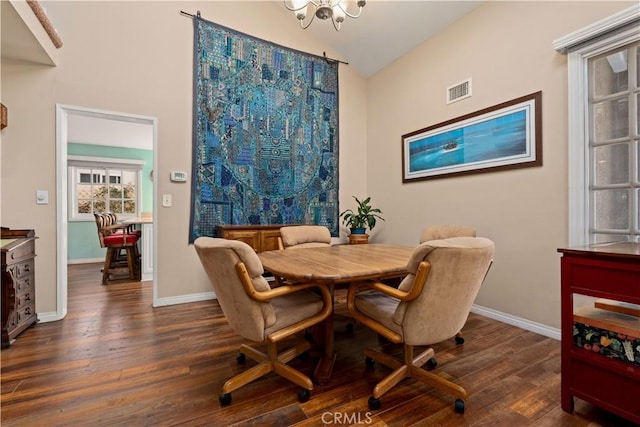 dining space featuring dark hardwood / wood-style floors, a notable chandelier, and vaulted ceiling