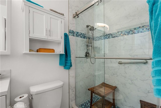 bathroom with a shower with shower door, toilet, and vanity