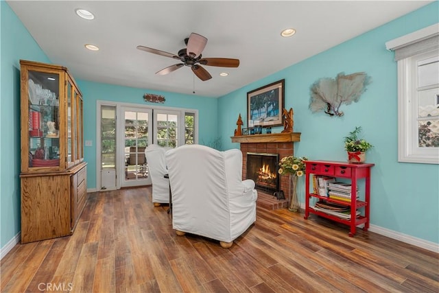 living room with ceiling fan, a fireplace, and dark wood-type flooring