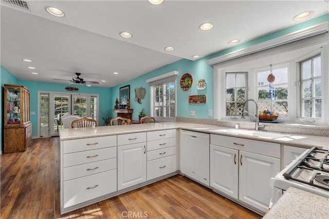 kitchen with white appliances, white cabinetry, sink, kitchen peninsula, and hardwood / wood-style flooring