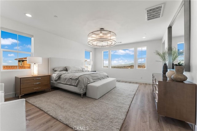 bedroom featuring hardwood / wood-style flooring, an inviting chandelier, and multiple windows